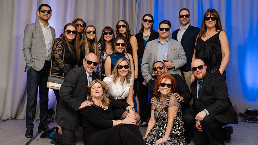 Sales team sporting sunglasses in a team photo at the Sales Awards.