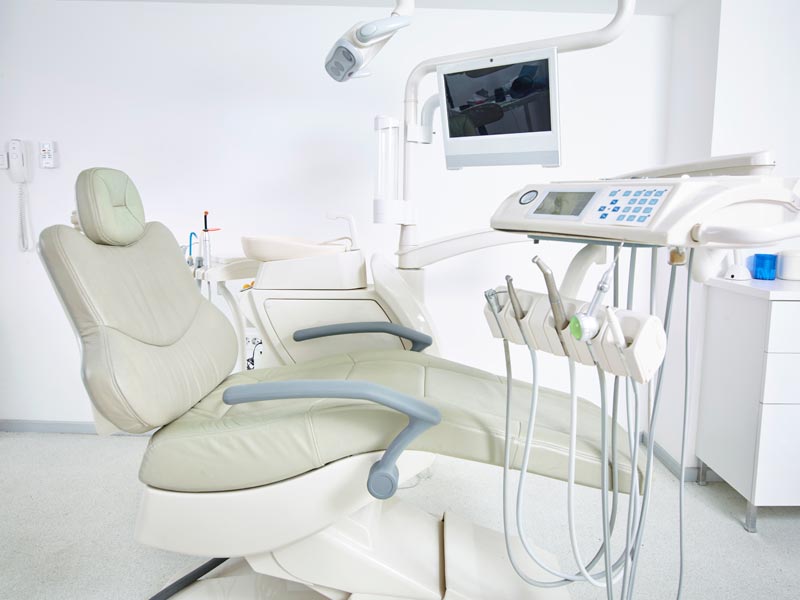 A modern dentist's chair surrounded by other dental equipment
